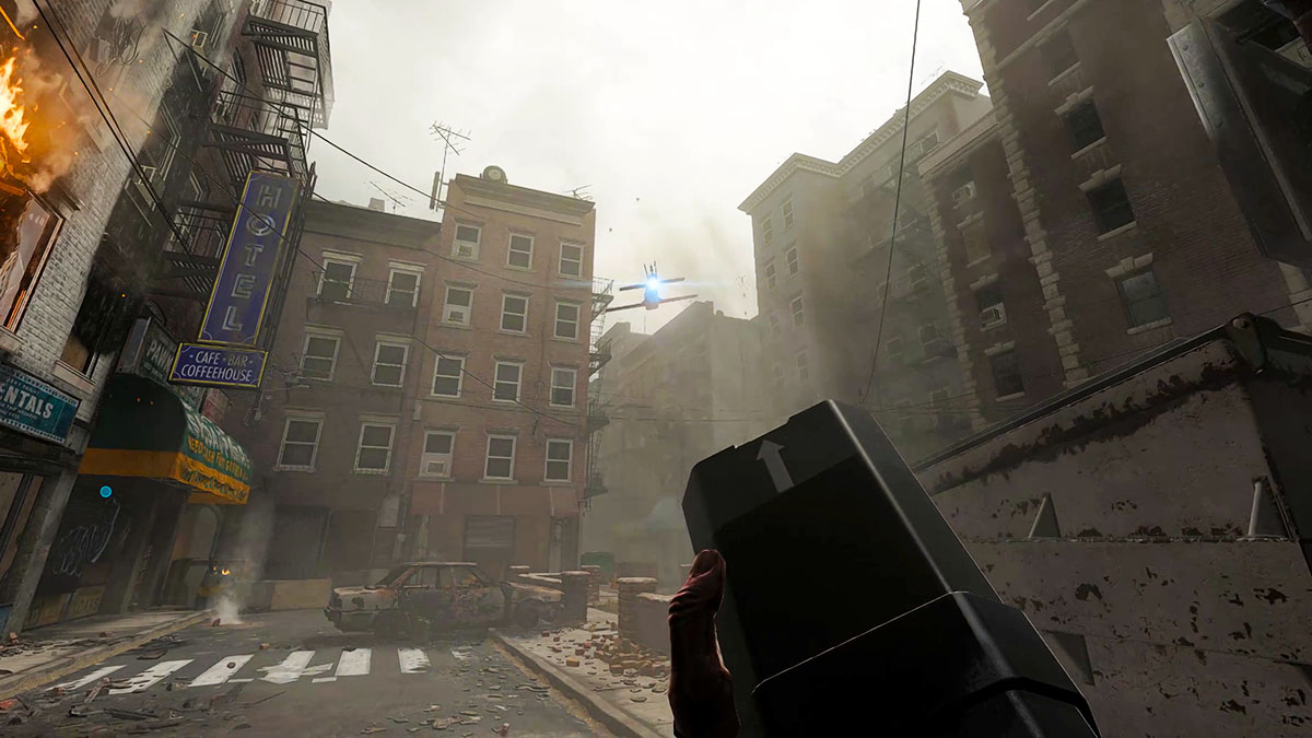 A player hand holding a remote as a drone flies between buildings.
