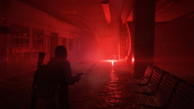 Ellie walking through dark subway lit by a red flare.