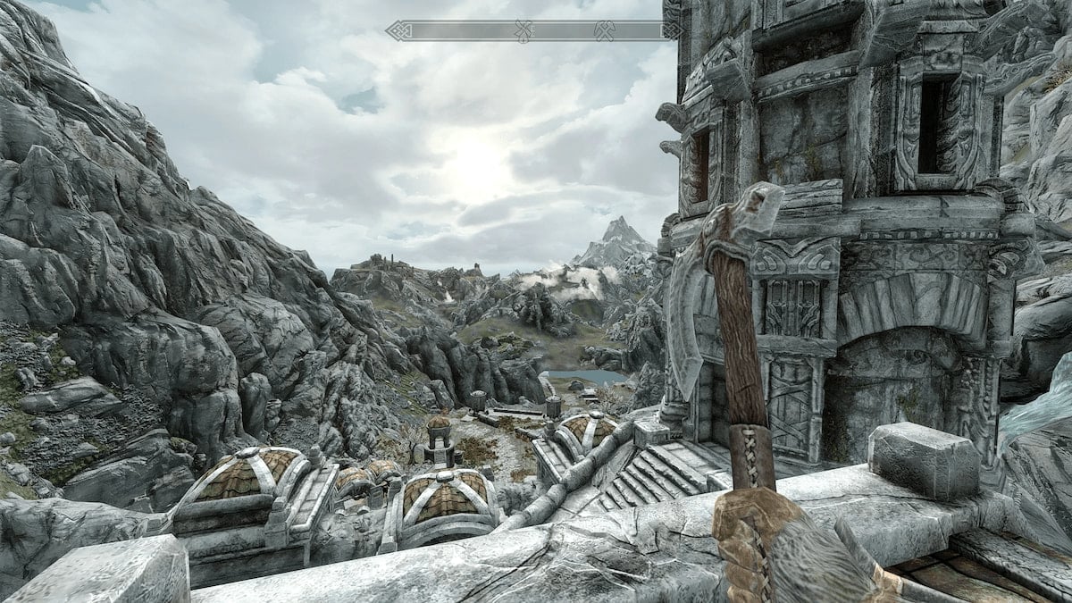 Player holding an axe looking out at snowy mountain landscape from the top of ruins