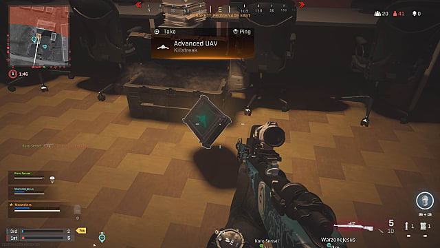 A player holding a marksman rifle, looking at an advanced UAV killstreak floating on the floor near a crate.