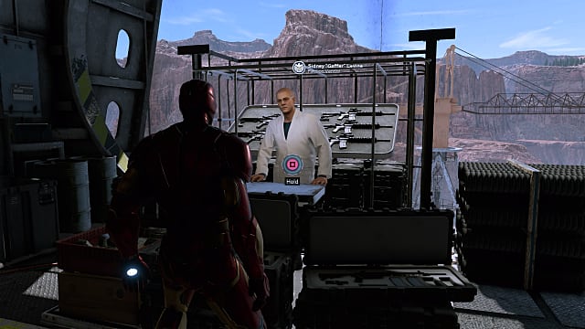 Iron Man standing in front of Sidney Levine's shop in the hangar of the Helicarrier. 