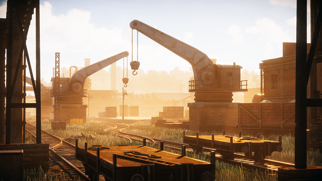 Cranes sit idle at the edge of an industrial railyard in the early morning, smoke stacks in the distance.