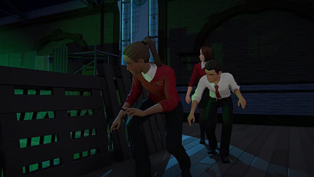 Donna, wearing a red vest and black pants, crouching behind pallets alongside another man and woman
