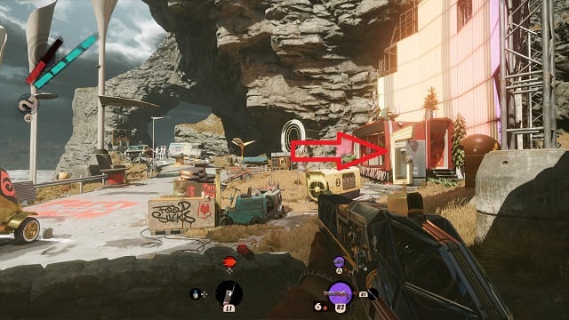 The player character looking toward a cliff face with a bright neon sign on the right and concrete barriers in them middle.