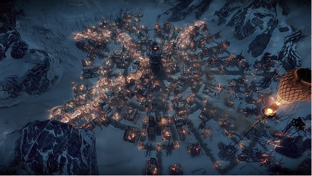 A bright circular settlement sits in a valley between snow covered mountains