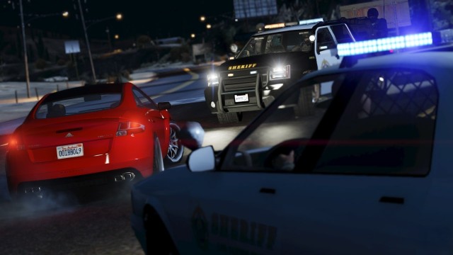 A police SUV and patrol car stop a red sports car.