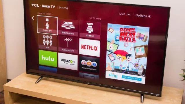 A TCL's P-Series 55-ion TV sits on a TV stand and shows its main menu with red background