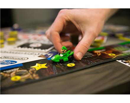 A player's hand moving the Luigi token around the Monopoly board