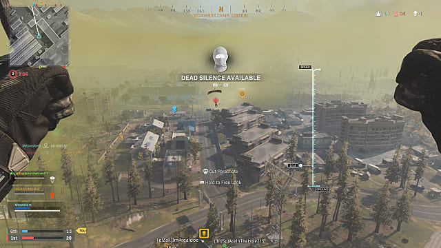 A player parachuting into the map over a grove of trees and buildings, tagging other players.