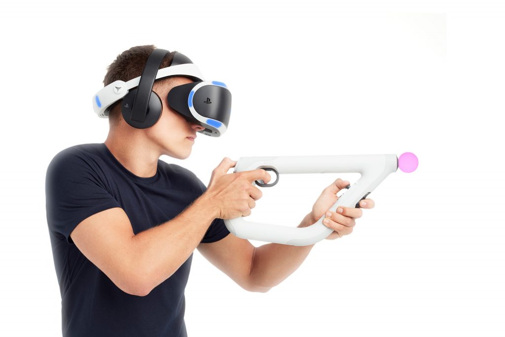 a man wearing a black shirt wears a PSVR and wields a gun peripheral with two Move controllers attached to it