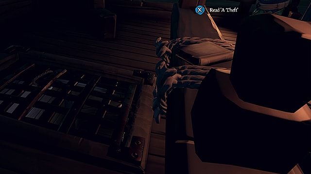 A journal sitting on a wooden railing between two pieces of rope, overlooking the hatch to the ship's hold.