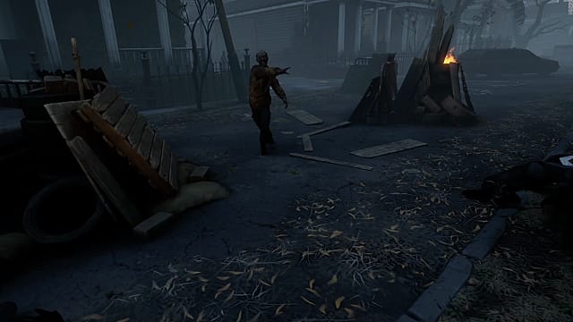 A zombie walking down a dark street towards a barrel fire in The Walking Dead: Saints & Sinners